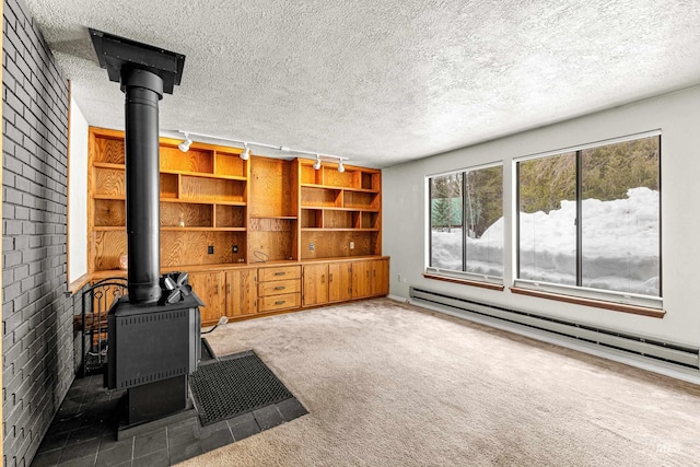 living area with a wood stove, a textured ceiling, a baseboard heating unit, and carpet flooring