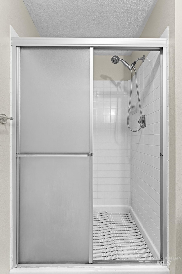 full bathroom with a stall shower and a textured ceiling