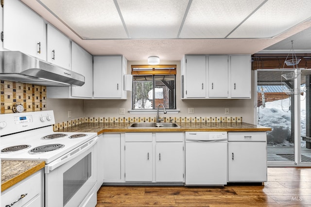 kitchen with under cabinet range hood, white appliances, dark wood-style flooring, a sink, and white cabinets