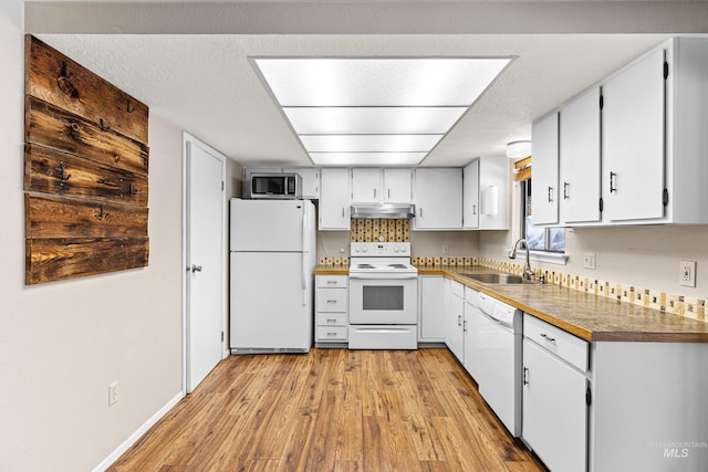 kitchen with light wood finished floors, white cabinets, a sink, white appliances, and under cabinet range hood