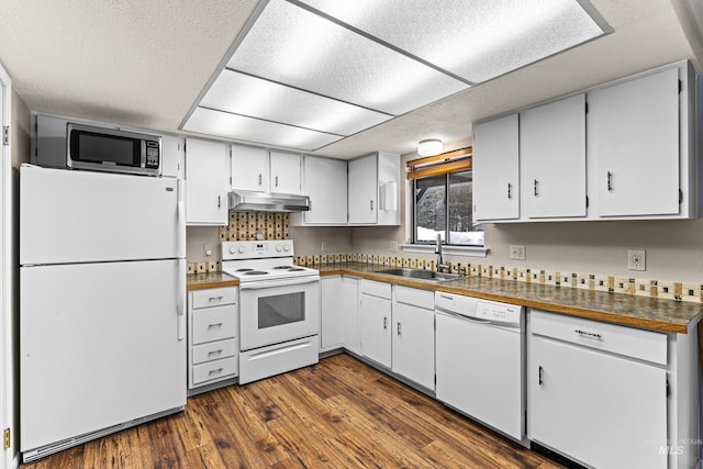 kitchen featuring dark countertops, dark wood-type flooring, a sink, white appliances, and under cabinet range hood