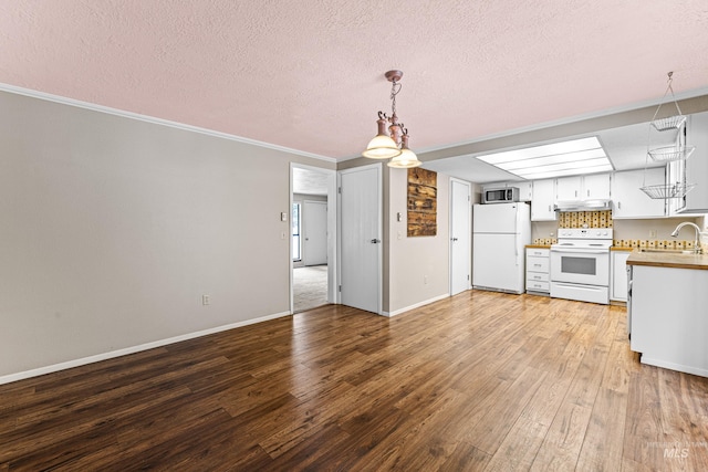 interior space featuring white appliances, decorative backsplash, light wood-type flooring, under cabinet range hood, and white cabinetry