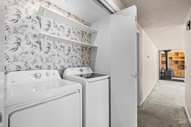 washroom with laundry area, a wood stove, a textured ceiling, washer and dryer, and carpet floors