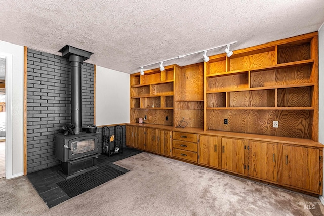 interior space featuring a textured ceiling, carpet, and a wood stove