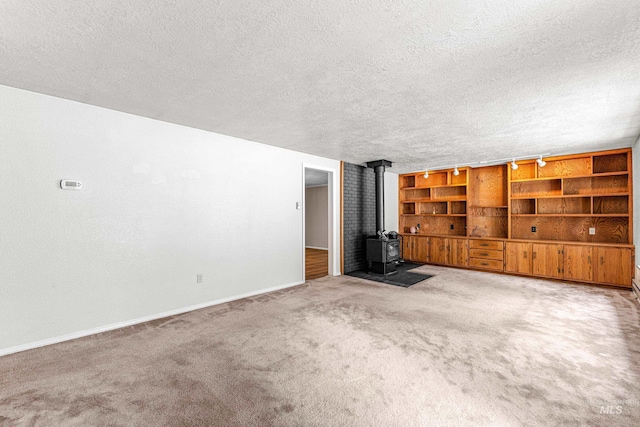 unfurnished living room featuring carpet, a wood stove, and a textured ceiling