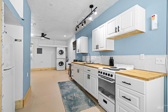 kitchen with electric range, a ceiling fan, stacked washer and clothes dryer, butcher block countertops, and a sink