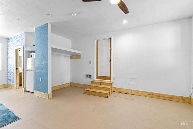 interior space featuring visible vents, a ceiling fan, freestanding refrigerator, and baseboards