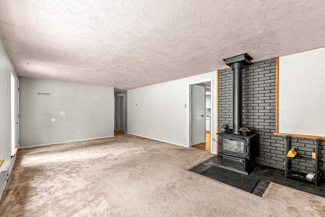 unfurnished living room featuring carpet floors, a wood stove, and a textured ceiling