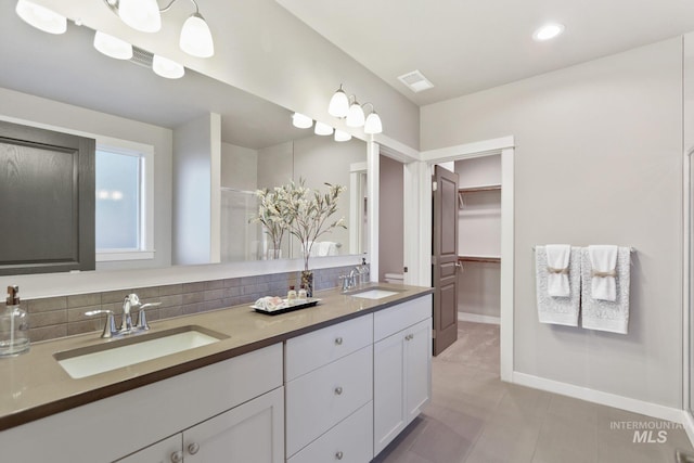 bathroom featuring tile patterned flooring, vanity, walk in shower, and decorative backsplash