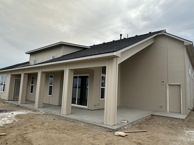 rear view of property with roof with shingles and a patio area