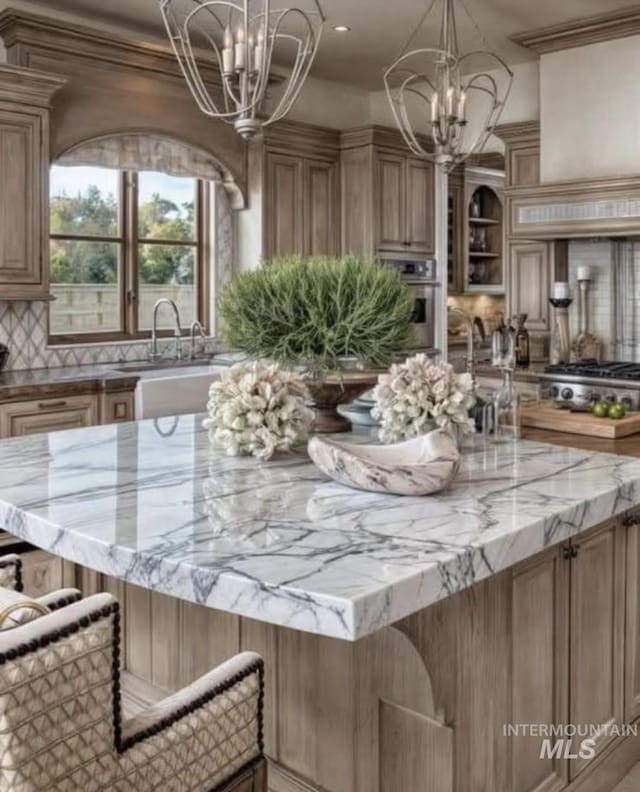kitchen featuring an inviting chandelier, a sink, appliances with stainless steel finishes, and light stone counters