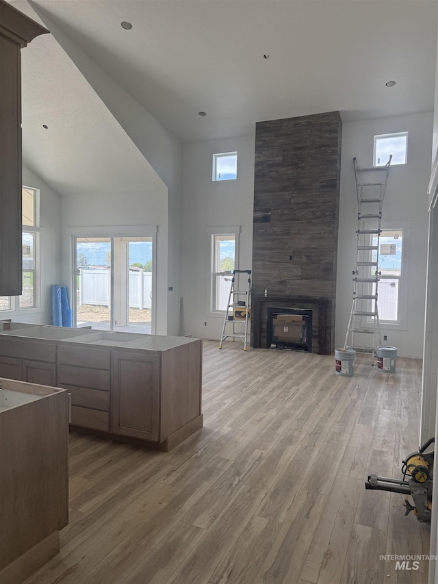 kitchen featuring a high ceiling, open floor plan, a large fireplace, and light wood-style floors