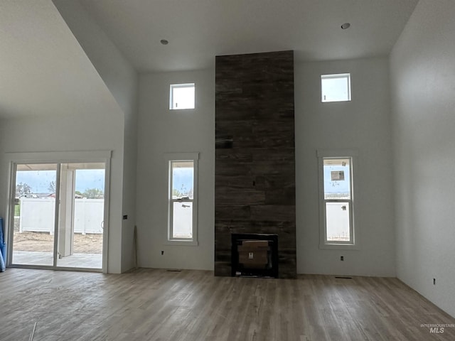 unfurnished living room with a towering ceiling, wood finished floors, and a healthy amount of sunlight