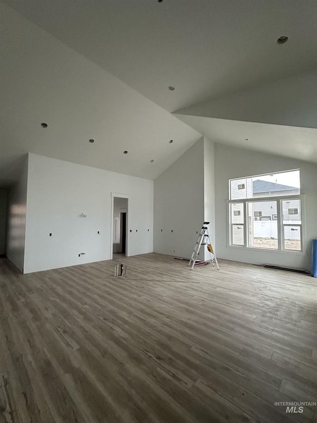 unfurnished living room featuring wood finished floors and high vaulted ceiling