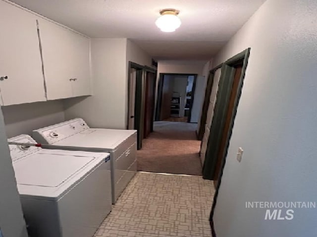 laundry area featuring separate washer and dryer, cabinet space, and light carpet