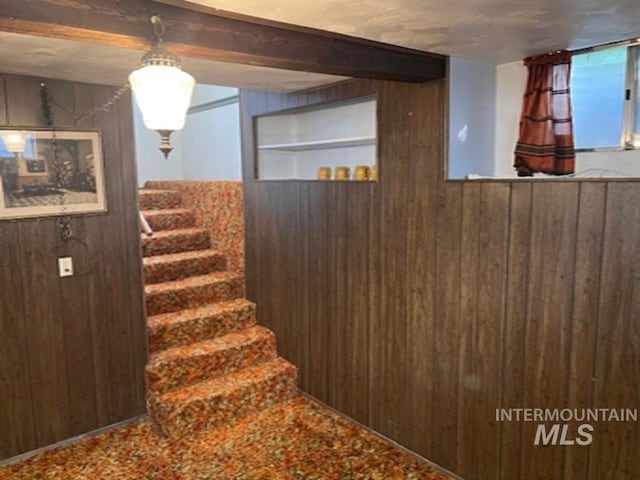 stairs featuring wooden walls and beam ceiling