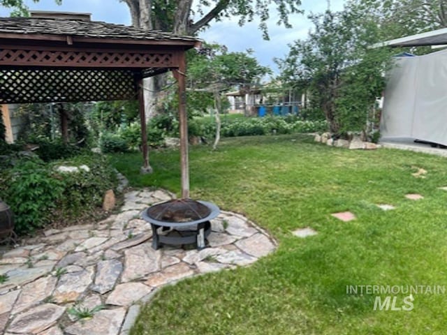view of green lawn featuring an outdoor fire pit