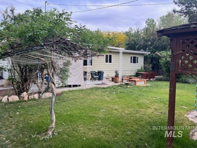 rear view of house featuring a lawn and a patio