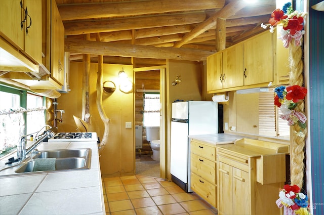 kitchen featuring beamed ceiling, sink, light tile floors, and tile countertops