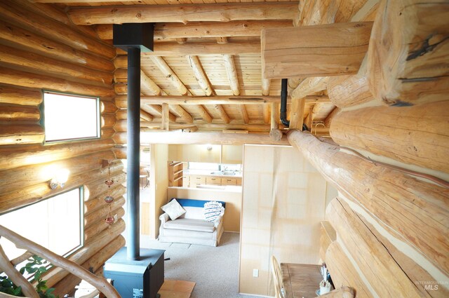 interior space with multiple windows, carpet, and a wood stove