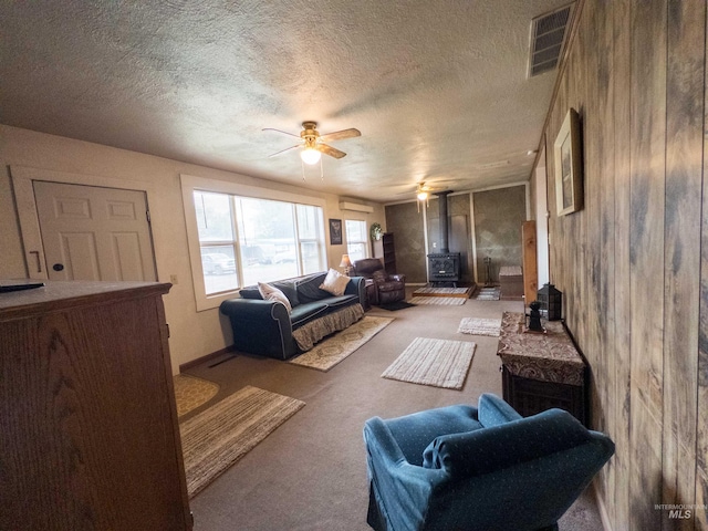 300 S Morgan Ave, New Meadows, ID 83654 - living area featuring a wood stove, a ceiling fan, carpet floors, an AC wall unit, and a textured ceiling