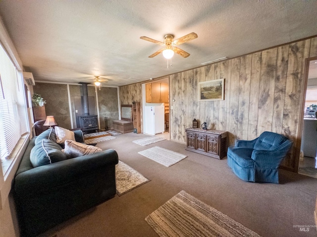 300 S Morgan Ave, New Meadows, ID 83654 - living room with a wood stove, a ceiling fan, wooden walls, carpet floors, and a textured ceiling