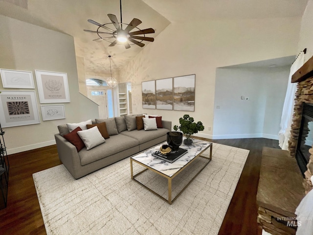 living room with ceiling fan with notable chandelier, a fireplace, dark hardwood / wood-style flooring, and high vaulted ceiling