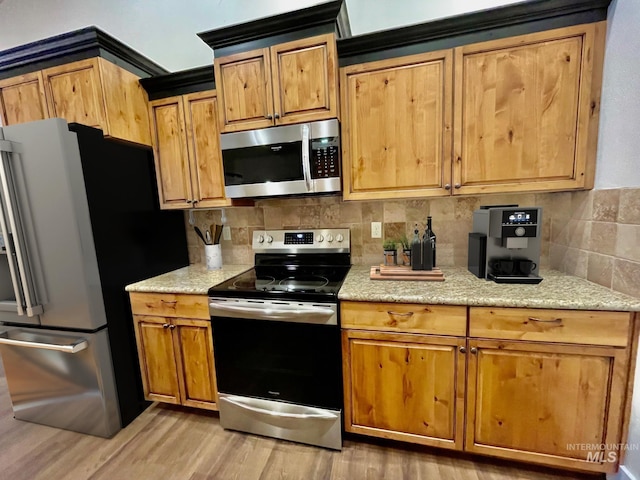 kitchen featuring light stone counters, stainless steel appliances, decorative backsplash, and light hardwood / wood-style flooring