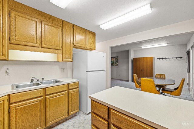 1718 Warren Wagon Rd, Mccall, ID 83638 - kitchen with freestanding refrigerator, a sink, light countertops, and brown cabinets