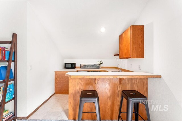 11151 W Hinsdale St, Boise, ID 83713 - kitchen with black microwave, a sink, vaulted ceiling, light countertops, and a peninsula