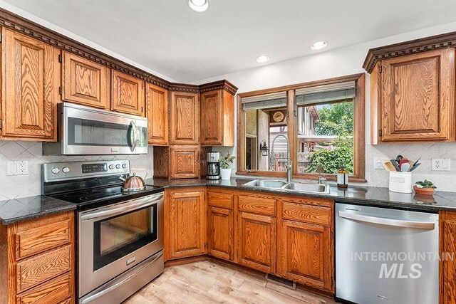 11151 W Hinsdale St, Boise, ID 83713 - kitchen featuring appliances with stainless steel finishes, a sink, brown cabinetry, backsplash, and light wood-style floors