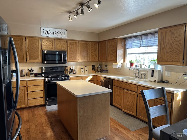 kitchen featuring sink, a center island, wood-type flooring, black appliances, and decorative backsplash