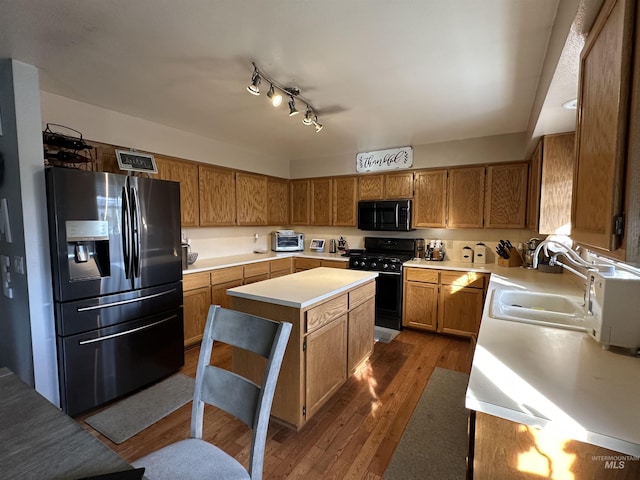 kitchen with a center island, sink, dark hardwood / wood-style flooring, and black appliances