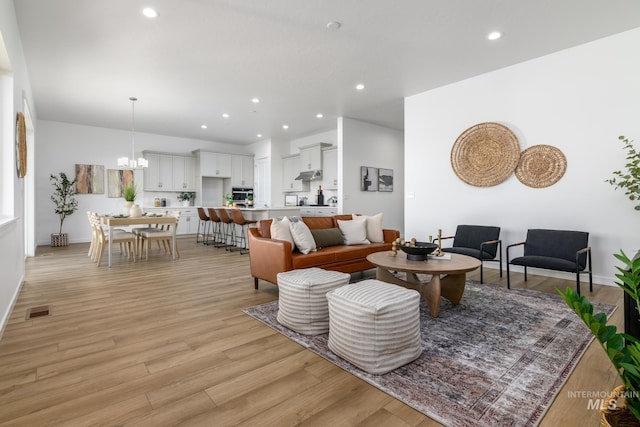 living room featuring a chandelier and light wood-type flooring