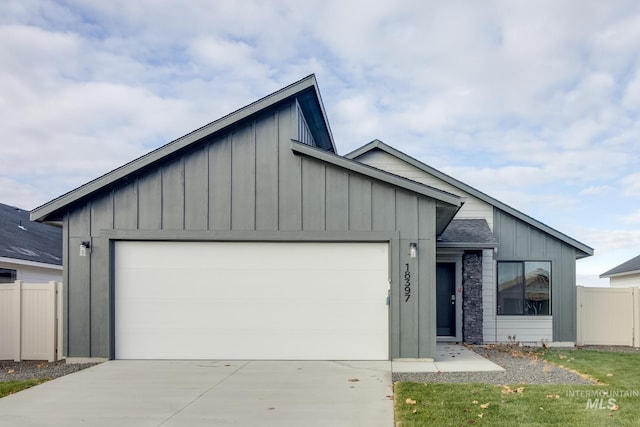 view of front of home with concrete driveway, board and batten siding, an attached garage, and fence