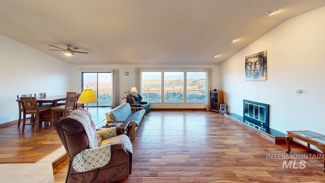 living room featuring hardwood / wood-style flooring, vaulted ceiling, and ceiling fan