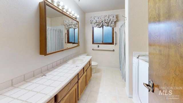 bathroom with separate washer and dryer, vanity, tile patterned flooring, and toilet