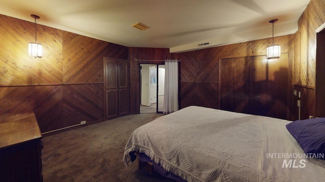 carpeted bedroom featuring wood walls