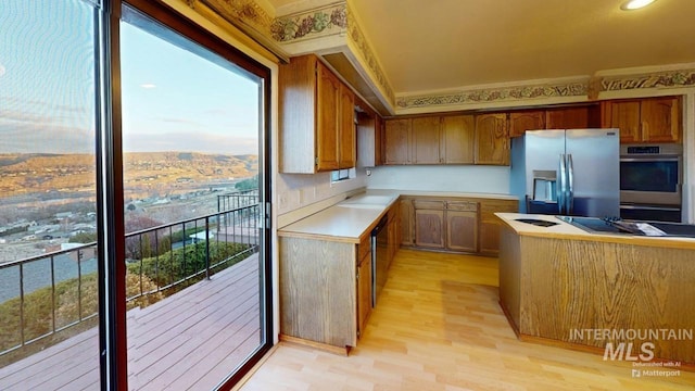 kitchen with a healthy amount of sunlight, appliances with stainless steel finishes, and light wood-type flooring