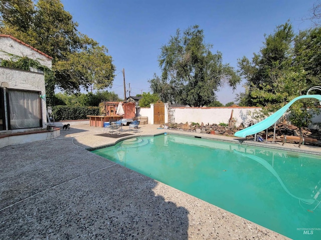 view of pool with a water slide and a patio area