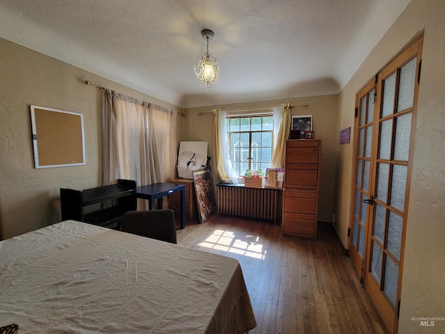 bedroom with radiator heating unit, wood-type flooring, and a textured ceiling