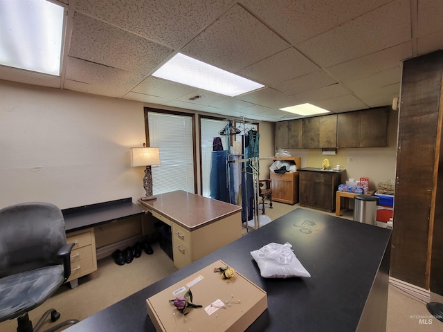 carpeted office with a paneled ceiling