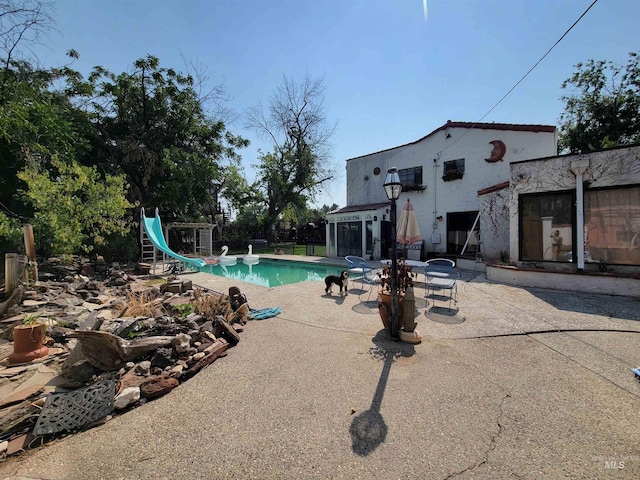 view of pool with a water slide and a patio area