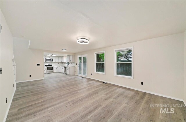 unfurnished living room featuring light wood-style floors and baseboards