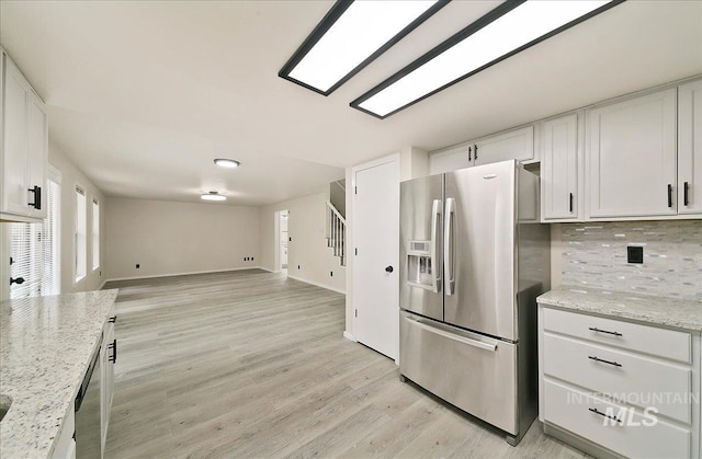 kitchen with stainless steel refrigerator with ice dispenser, white cabinets, light wood finished floors, open floor plan, and baseboards