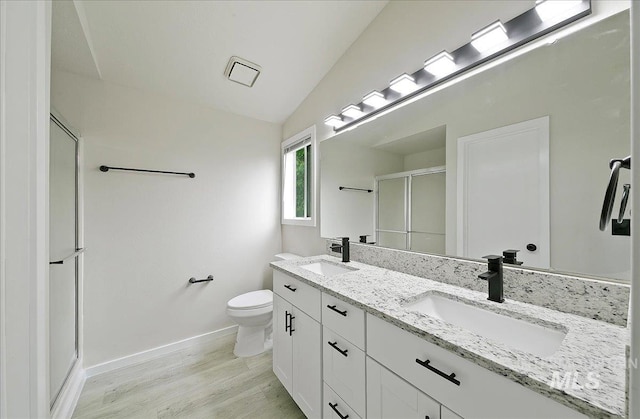 full bath with a stall shower, toilet, wood finished floors, baseboards, and double vanity