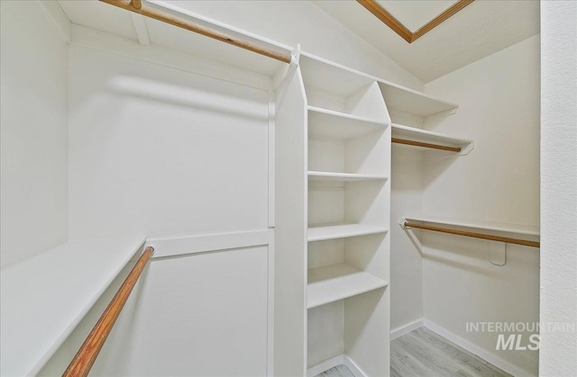 walk in closet featuring wood finished floors and vaulted ceiling