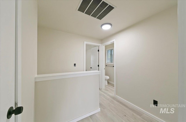 corridor with light wood-style flooring and baseboards