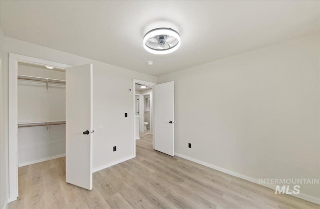 unfurnished bedroom with light wood-style floors, baseboards, and a closet