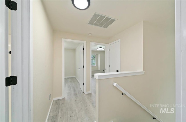corridor featuring light wood-style floors, an upstairs landing, and baseboards